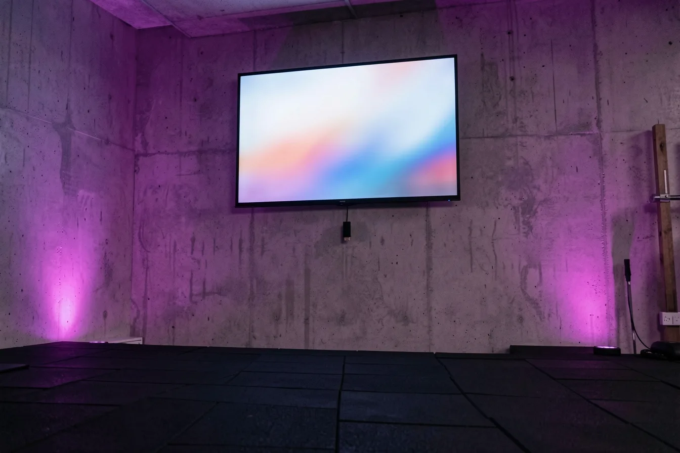Wall-mounted screen in an empty gym with a digital signage player stick plugged into the back
